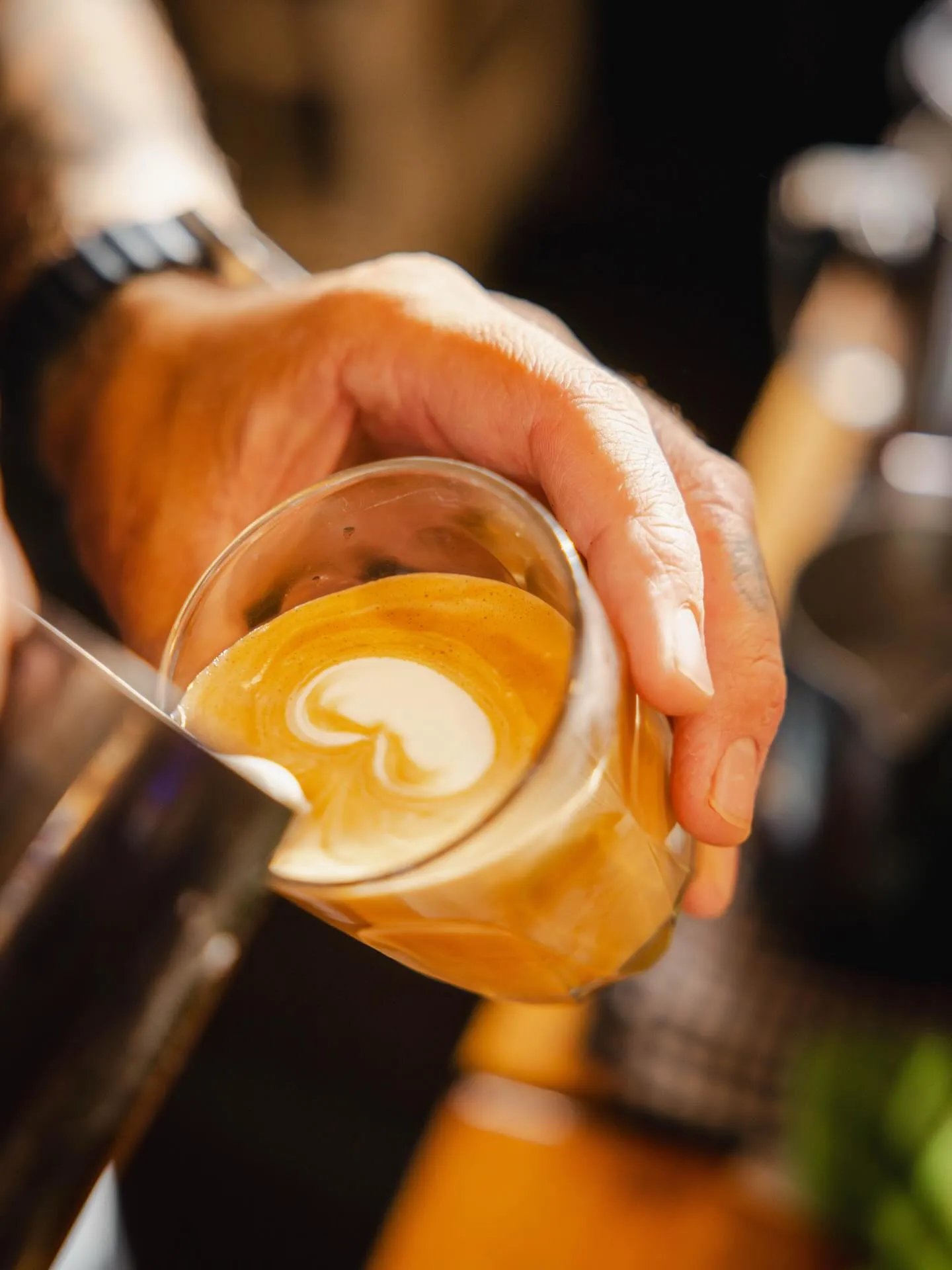 Close-up of golden latte art being poured into a glass