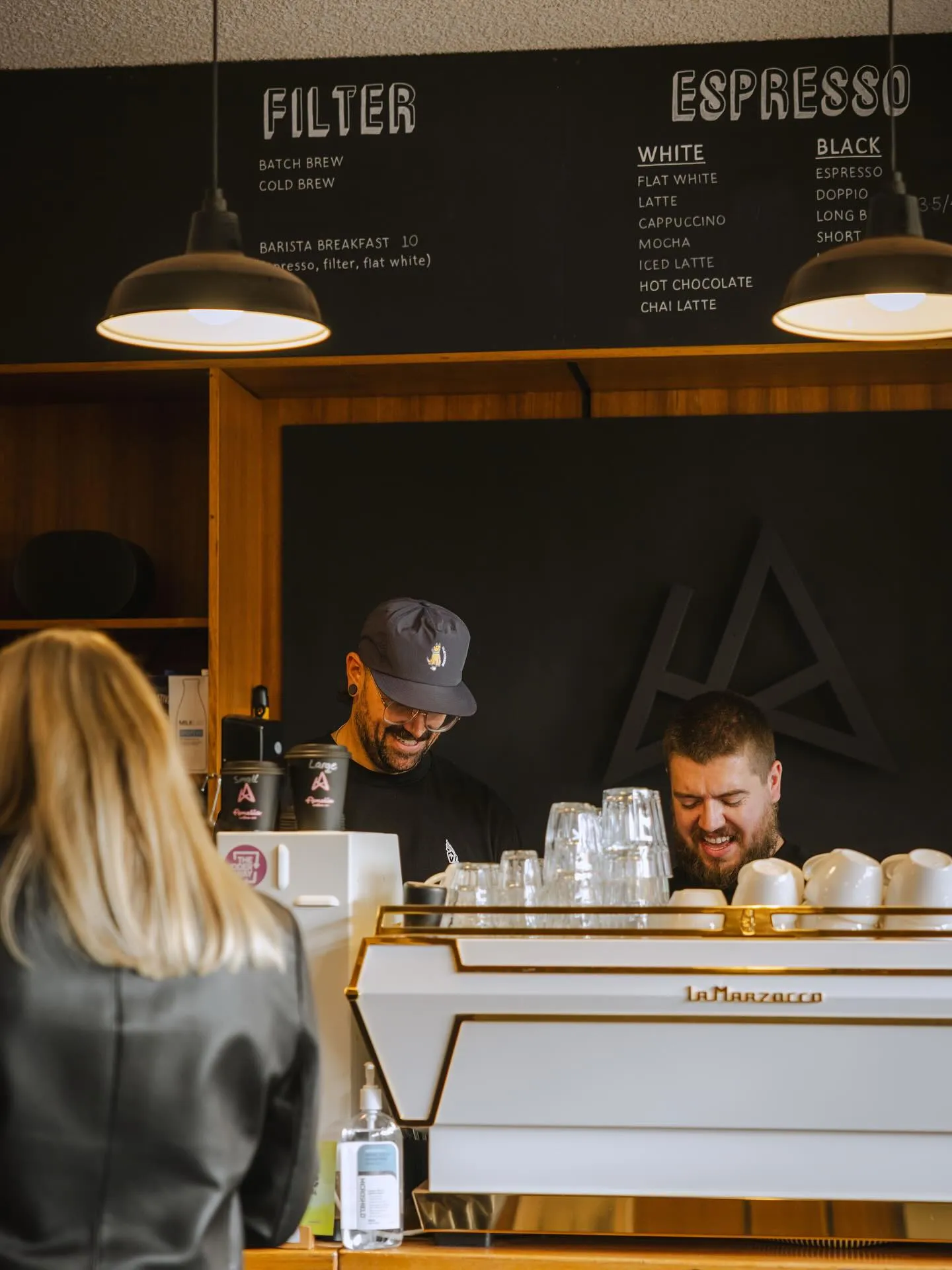 Baristas laughing together behind the counter at Amelia Coffee Co.